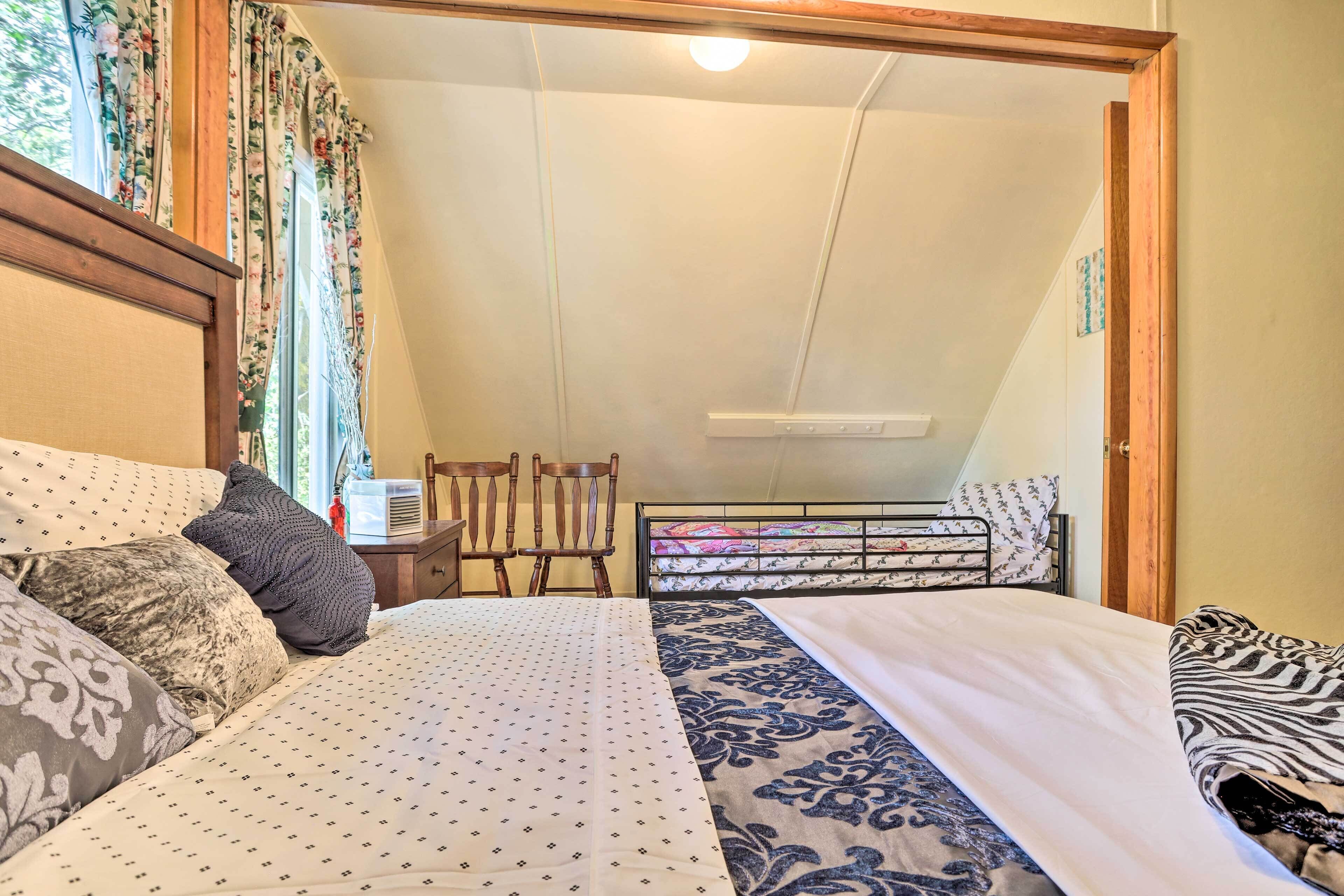 Ein Schlafzimmer mit Bett, Nachttisch, Stuhl und einem Fenster mit Vorhängen.