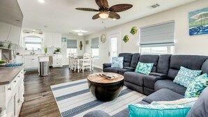 Ein modernes Wohnzimmer mit einem dunkelgrauen Sofa, einem runden Couchtisch und einem Deckenventilator.