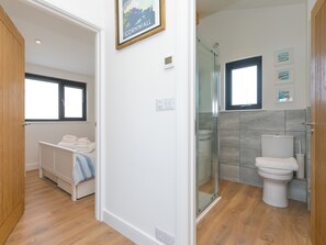 A modern bathroom with a shower, toilet, and a small window. - The Sandbox (Hayle)