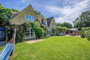 Ein traditionelles Steinhaus mit gepflegtem Rasen und einer Außenbereich-Sitzgelegenheit.