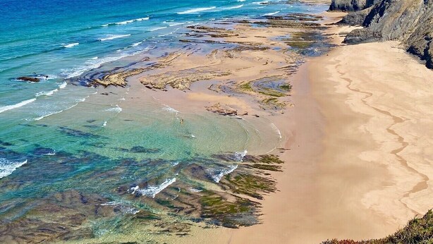 Un paisaje costero con una playa arenosa y acantilados rocosos.