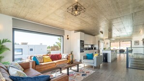 Amplia sala de estar con un sofá grande, una mesa de centro y un comedor con mesa y sillas.
