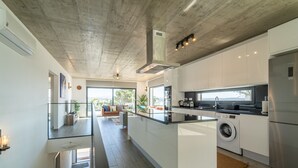 Una cocina moderna con una isla central, electrodomésticos integrados y un amplio ventanal con vistas al exterior.