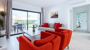 Ein modernes Wohnzimmer mit einer Couch, roten Sesseln, einem Couchtisch und einem Essbereich mit Stühlen und Tisch.