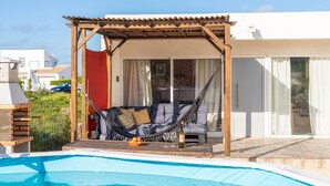 Zona de piscina amb un hamaca, una barbacoa i una piscina.