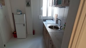 A compact kitchen with a refrigerator, sink, and cabinets. - 2 Bed Flat - Sleeps 5 - Parking - Wifi (Athens)