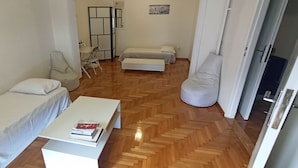 A compact living space with a sofa, a small table with books, a foldable chair, and a bed. - 2 Bed Flat - Sleeps 5 - Parking - Wifi (Athens)