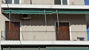 A multi-story building with balconies, awnings, and a visible air conditioning unit. - 2 Bed Flat - Sleeps 5 - Parking - Wifi (Athens)