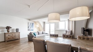 Ein geräumiger Wohnbereich mit einem Holzespeisetisch, Ledersesseln, einer Couch und einem Fernseher.