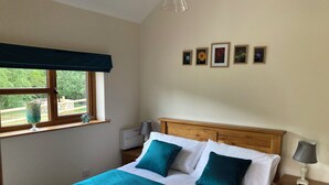 Un lit bien fait, recouvert d’une couvre-lit turquoise et blanche, avec une tête de lit en bois et une table de chevet surmontée d’une lampe.