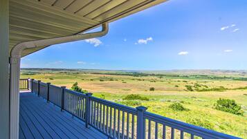 Une terrasse en bois avec une balustrade donnant sur un paysage verdoyant.
