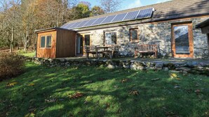Ein Steinhaus mit Holzanbau, Solaranlage und einer Steinmauer.