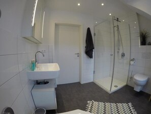 Une salle de bain moderne avec une douche à parois de verre, un lavabo blanc et des toilettes.