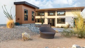 A modern two-story house with a flat roof, large windows, and a gravel driveway. - Contemporary Compound By Homestead Modern (Joshua Tree)