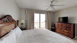 Une chambre d’hôtel avec un grand lit, une commode en bois, un ventilateur de plafond et un téléviseur.