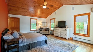 A bedroom with a bed, a dresser, a television, and a ceiling fan. - Hideaway at Highland Lake (Andover)
