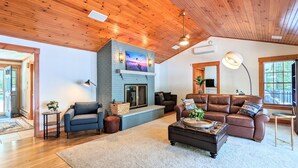 A spacious living room with a fireplace, leather sofas, and a large window. - Hideaway at Highland Lake (Andover)