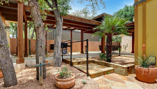 Un espace patio agrémenté d’une pergola, d’un palmier et d’un grand pot en terre cuite.