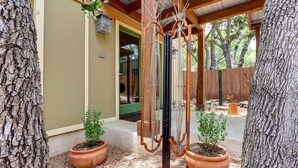 Un patio couvert doté d’un plafond en bois, de plantes en pot et d’une structure métallique.