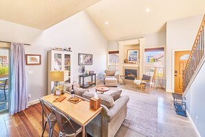 A spacious living area with a fireplace, a dining table, and a staircase.