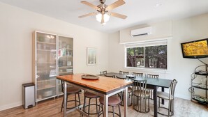 A dining area with a central table, bar stools, and a ceiling fan. - Three Sisters- Casita 1   I Pet Friendly couples retreat in Wimberley (Wimberley)