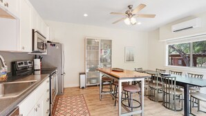 A modern kitchen with stainless steel appliances, a dining area with a wooden table and metal chairs, and a ceiling fan. - Three Sisters- Casita 1   I Pet Friendly couples retreat in Wimberley (Wimberley)