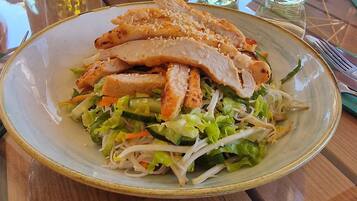 Prato de comida com frango grelhado e legumes sobre uma mesa.