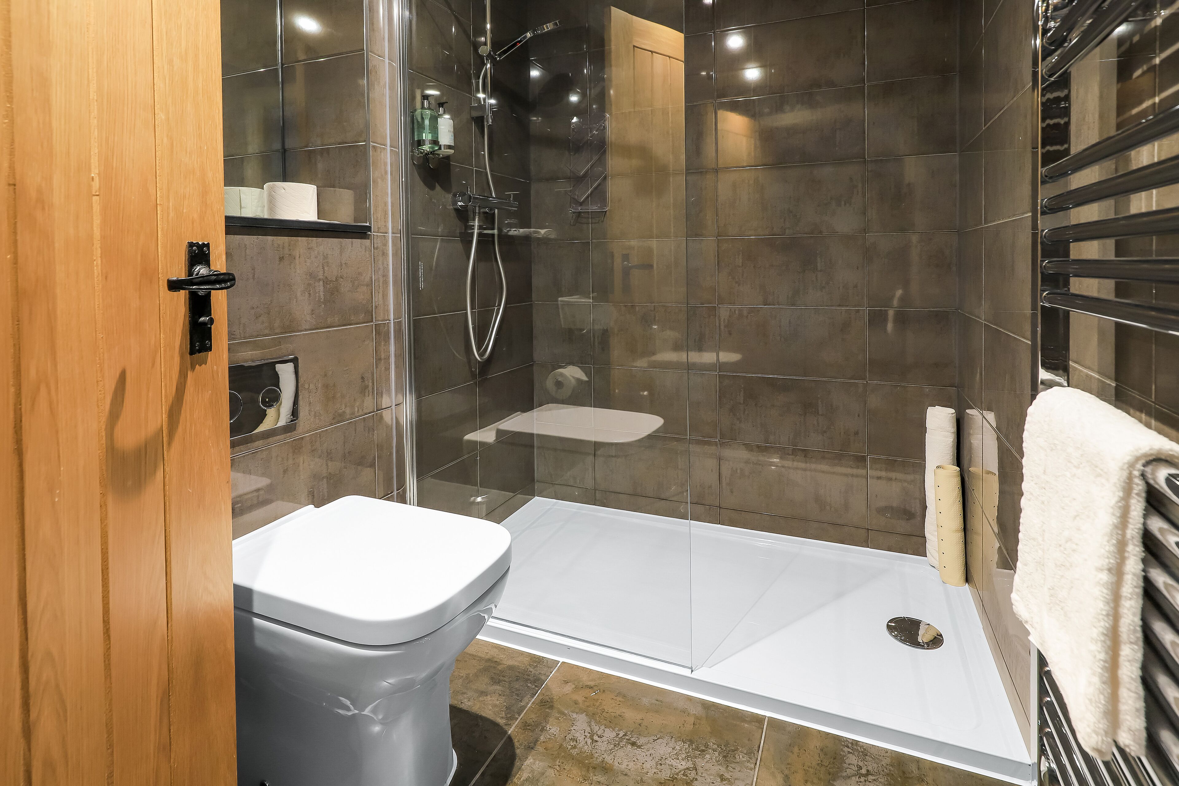 Un bagno moderno con cabina doccia in vetro, un water bianco e un porta asciugamani.
