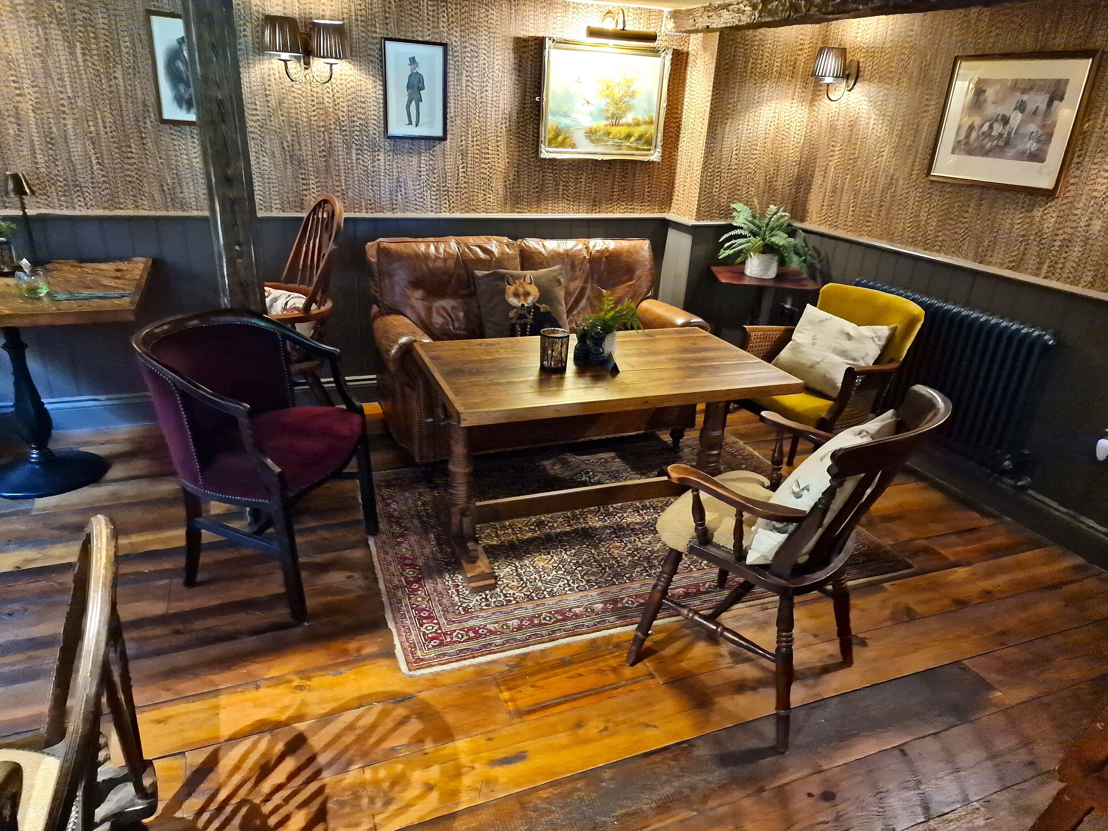 A cozy room with a wooden table, leather sofa, and patterned rug.