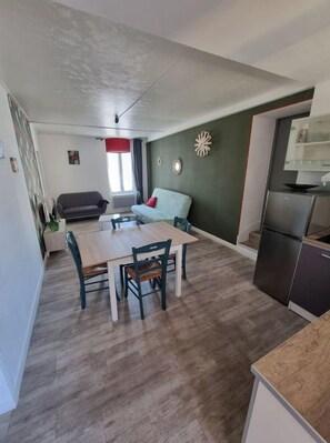 Cozy living space with a dining area and kitchenette, featuring a sofa, dining table, and refrigerator.