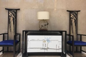 A reception desk with a white cabinet, two blue chairs, and a lamp on top. - Nanshanyuan Hotel (Xi'an)