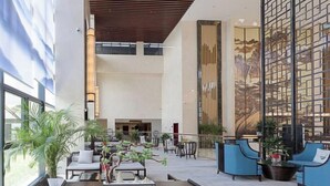 A spacious indoor area with seating arrangements, tables, and potted plants. - Nanshanyuan Hotel (Xi'an)