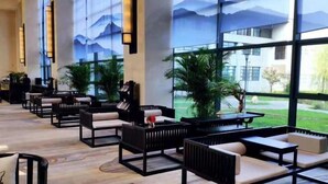 A modern hotel lobby with black and white seating, large windows, and a view of greenery. - Nanshanyuan Hotel (Xi'an)