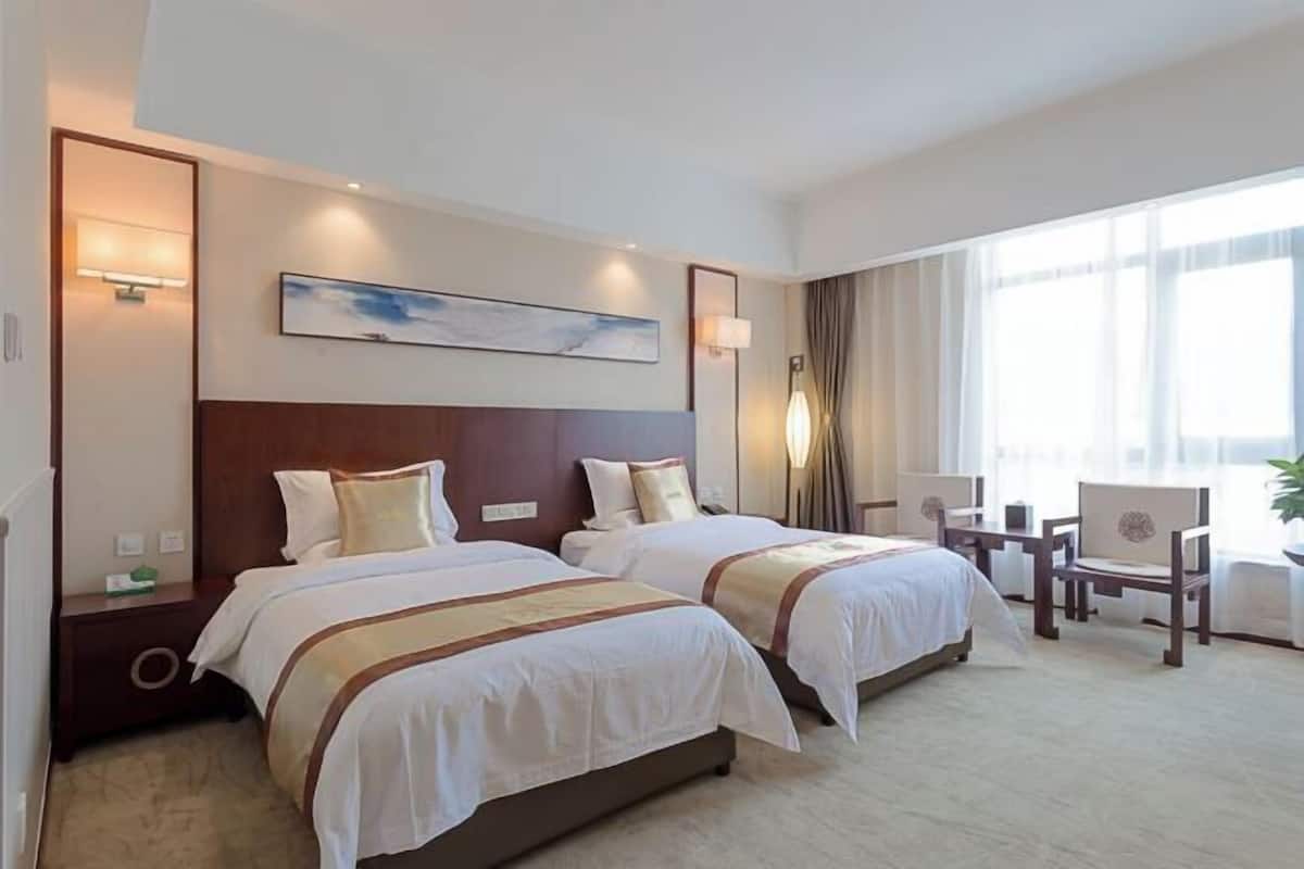 A hotel room with two beds, a desk, and a chair.