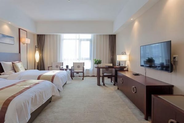 A hotel room with two beds, a desk, a chair, a TV, and a large window with curtains. - Nanshanyuan Hotel (Xi'an)