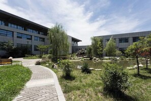 A building with a paved walkway, a pond, and surrounding greenery. - Nanshanyuan Hotel (Xi'an)