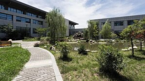 A modern building with a paved walkway, a small pond, and surrounding greenery. - Nanshanyuan Hotel (Xi'an)