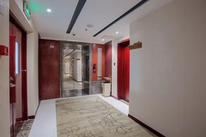 Un pasillo de hotel con alfombra, puertas y un espejo.