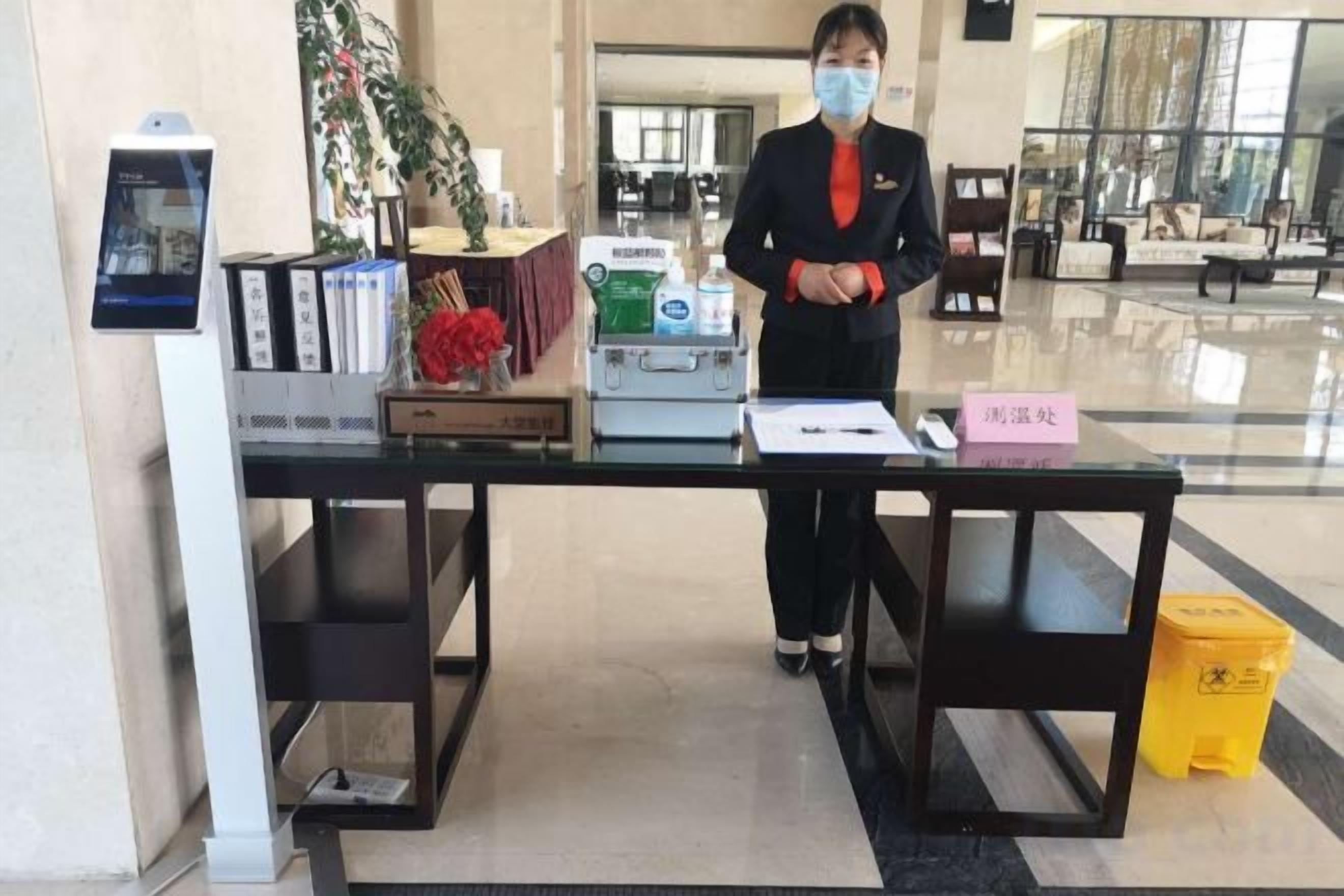 A reception desk with a digital display, a plant, a vase with flowers, and a sign with Chinese characters.