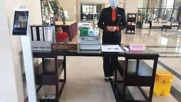 A reception desk with a digital display, a plant, a vase with flowers, and a sign with Chinese characters.