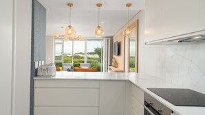 Una cocina moderna con una isla grande, armarios blancos y vistas al exterior.
