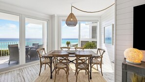 Un'area pranzo con tavolo e sedie, un lampadario e vista sull'oceano.