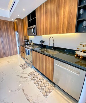 A modern kitchen with wooden cabinets, a stainless steel sink, and a built-in microwave.