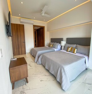 Ein Hotelzimmer mit zwei Betten, einem Fernseher, einem Schreibtisch und einem Deckenventilator.