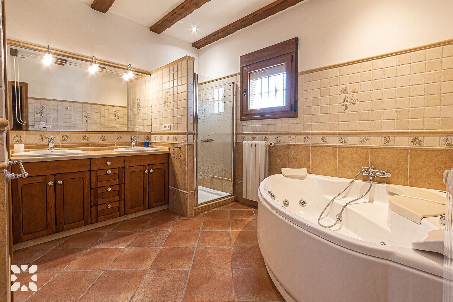 A bathroom with a double sink, a walk-in shower, a bathtub, and wooden cabinets.