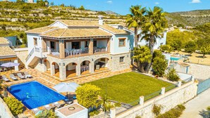 Une grande maison avec une piscine, un espace extérieur aménagé pour se détendre et une pelouse bien entretenue.