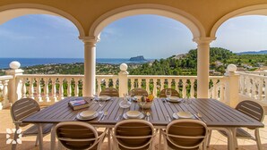 A table set for four with a view of the sea and hills in the background. - Villa TREVERIS by Abahana Villas (Teulada)