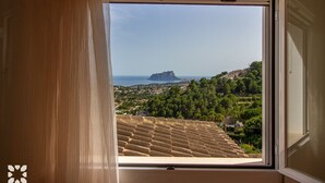 A window with a view of a coastal landscape, including a prominent hill and a distant island. - Villa TREVERIS by Abahana Villas (Teulada)