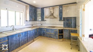 A modern kitchen with dark blue cabinets, a stainless steel sink, and a range hood. - Villa TREVERIS by Abahana Villas (Teulada)