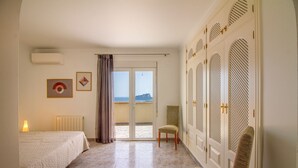A hotel room with a bed, a chair, a view of the sea, and a balcony. - Villa TREVERIS by Abahana Villas (Teulada)